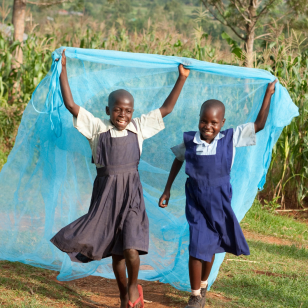 Two African girls are smiling and holding a blue net